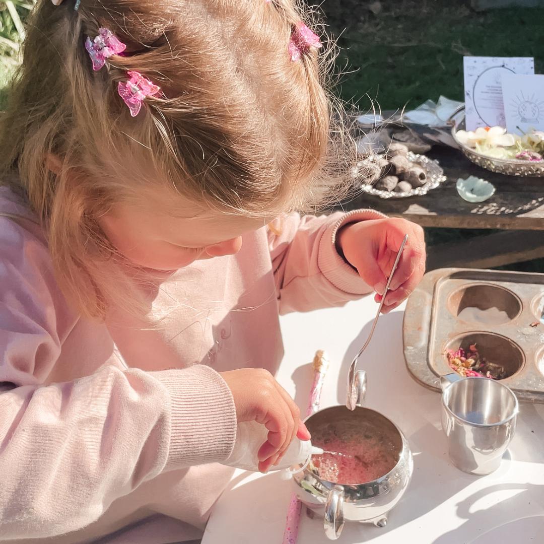 A magical potion kit by Sparkle & Spell Co., complete with colorful powders, a bowl, a special spoon, and a whimsical spell card, all laid out on a starry black tablecloth.