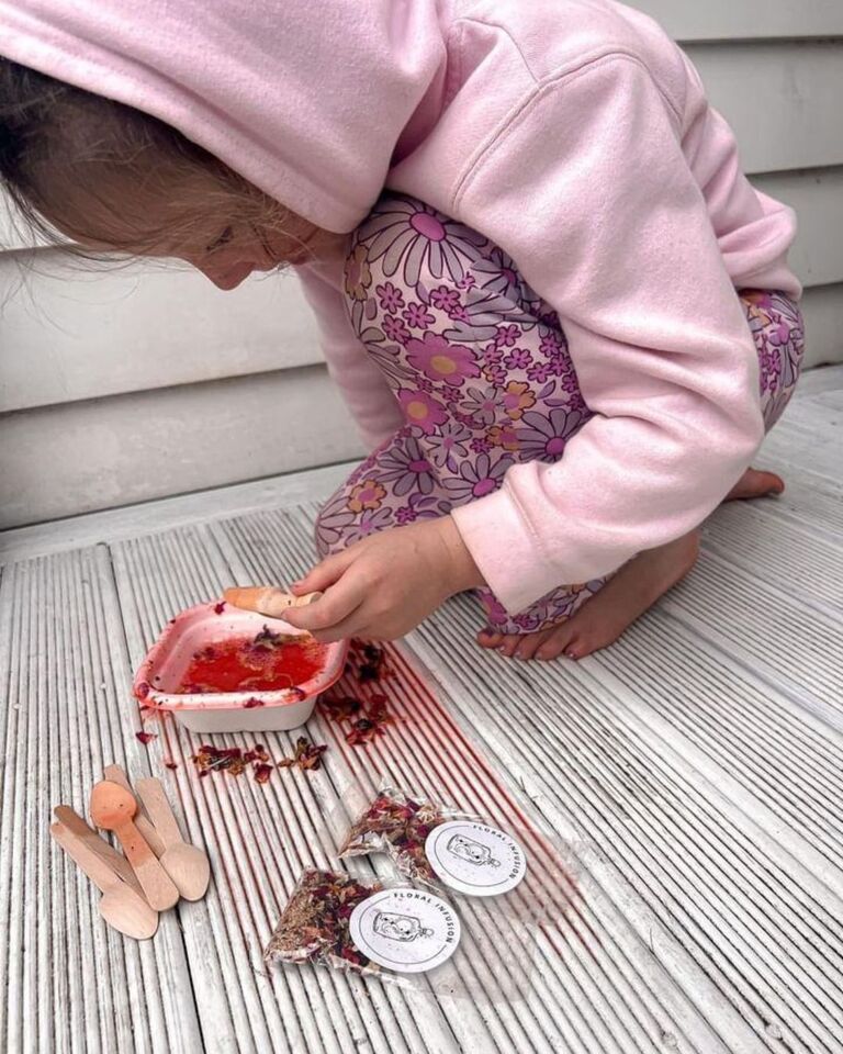 little girl in pink makes a bright red magic potion on the outside deck